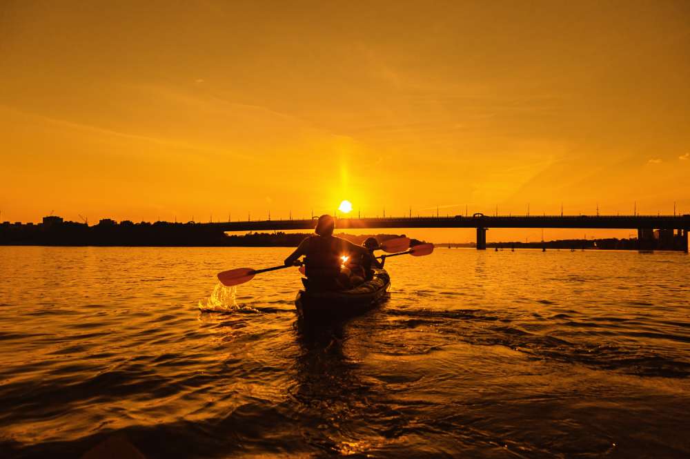 Night kayaking in Kochi with kayaks gliding through calm backwaters under the starry sky and soft reflections on the water.