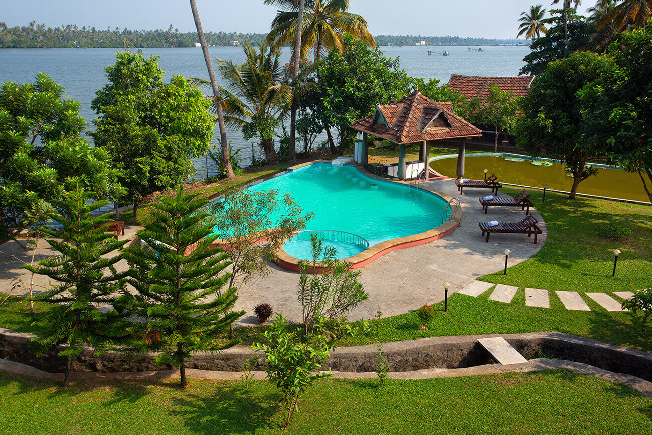 Infinity swimming pool at an Ayurveda resort in Kerala surrounded by lush greenery and peaceful nature views.